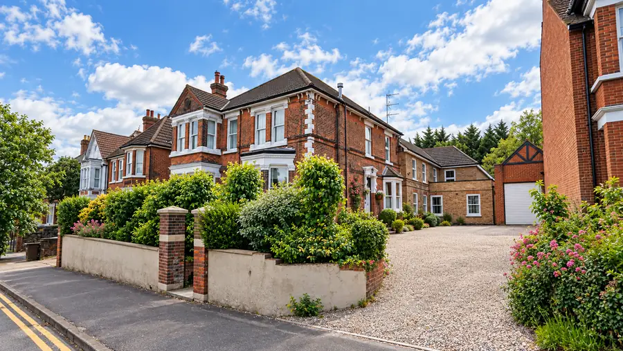 Acorn House seen from along Maidstone Road, with its side wing, a gravel drive and flowering shrubs