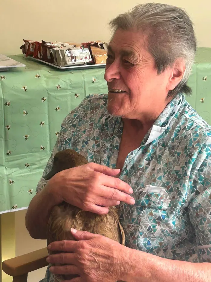 A resident cuddling a duck during an animal visit
