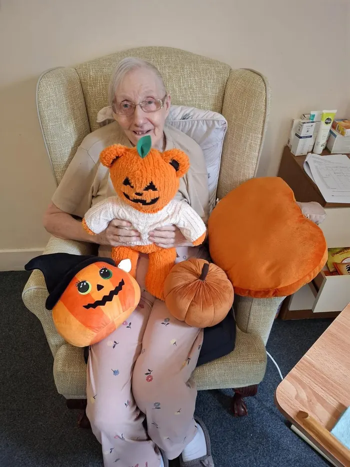 A resident in an armchair with pumpkin cushions for Halloween